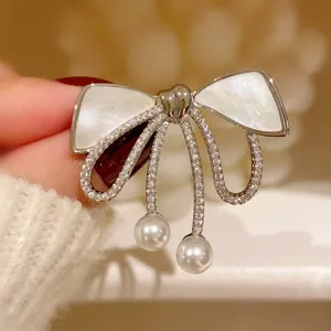Close-up detail shot of an elegant mother-of-pearl bow brooch with sparkling crystal pavé.