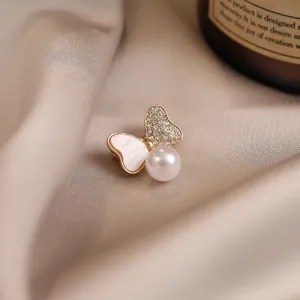 Elegant butterfly pearl brooch detail shot, gold-toned metal with crystals and faux pearl.