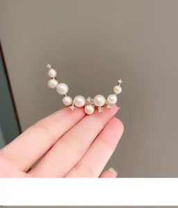 Detailed close-up of an elegant pearl crescent brooch with shiny rhinestones and pearls.