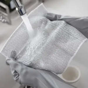 Gros plan détail d'un chiffon vaisselle en fil d'argent lavé sous l'eau courante.