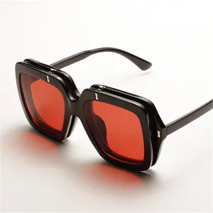 Vista detallada de gafas de sol cuadradas de gran tamaño con montura negra y lentes rojas