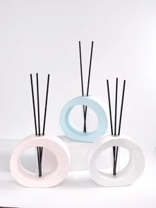 Gedetailleerde opname van een moderne minimalistische holle ring diffuser vaas met zwarte stokjes.