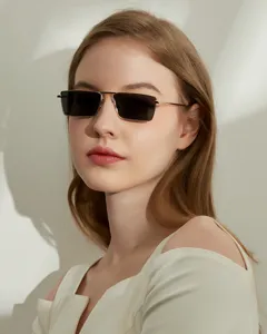 Detailed close-up of a model wearing small rectangular gold metal frame sunglasses