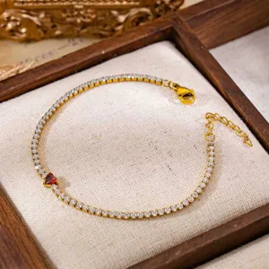 Detail van gouden tennisarmband met zirkonia en een rode hartvormige edelsteen voor dames