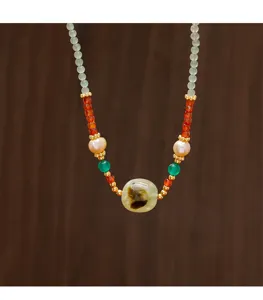Detailed view of a handmade necklace featuring pearls, red agate, and prehnite stones