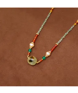 Detail of handmade necklace with freshwater pearls, red agate, and prehnite stone