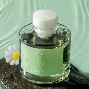 Flacone di olio essenziale in vetro con etichetta verde su pietra e sfondo d'acqua