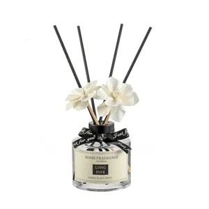 Modern home reed diffuser set with elegant glass bottle, black sticks and white flower decor.