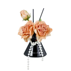 Artificial rose reed diffuser set, elegant home fragrance decor with black vase and pearls.