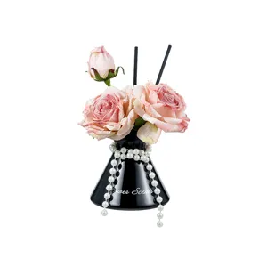 Decorative reed diffuser set with artificial pink roses, black vase and pearls for home decor.