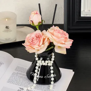Artificial rose reed diffuser set with black vase and pearls for elegant home decoration.