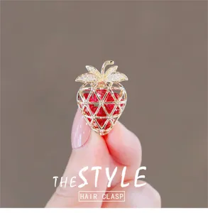 Detail view of the elegant gold strawberry brooch with red crystals and sparkling rhinestones.