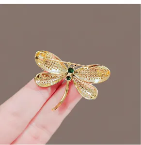 Close-up detail of the delicate gold rhinestone dragonfly brooch showing exquisite crystal wings.