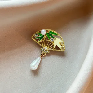 Détail en gros plan de la broche éventail de style chinois avec bambou vert, perles et strass.