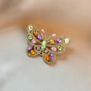 Exquisite butterfly brooch detail showing colorful crystal rhinestones and shiny gold metal finish.