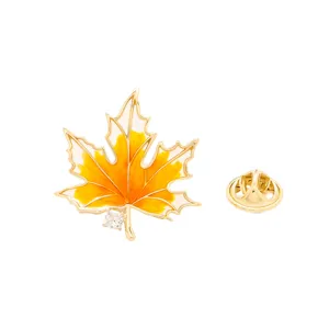 Vue détaillée de la broche feuille d'érable dorée avec émail jaune et un cristal étincelant.