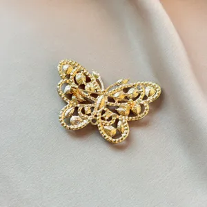 Close-up view of the back pin and textured metal structure of a gold butterfly brooch.