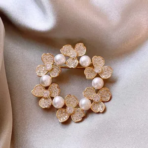 Detailed close-up of the elegant crystal rhinestone clover and pearl wreath brooch accessory.
