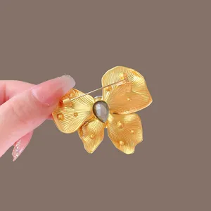 Close up of exquisite gold butterfly brooch with gray crystal stone, elegant suit accessory.