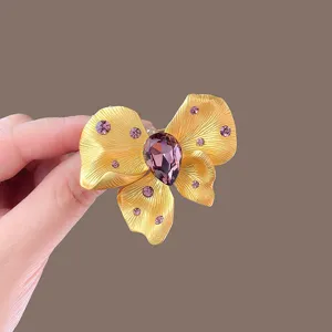 Exquisite crystal butterfly brooch detail shot, showing the brushed gold texture and purple gemstone.