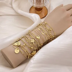 Macro view of layered 18K gold plated stainless steel bracelets with heart and star charms