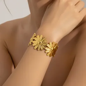 Nahaufnahme des vergoldeten Edelstahl-Armreifs mit Blumenmuster am Handgelenk des Modells