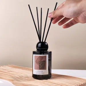 Minimalist reed diffuser set with black glass bottle and wooden tray for home decor.