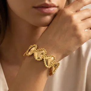 Detaillierte Nahaufnahme eines 18K vergoldeten herzförmigen Perlenarmbands am Handgelenk