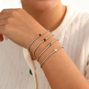 Close-up van vier delicate hartvormige zirkonia tennisarmbanden om een vrouwenpols