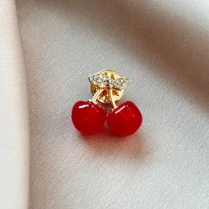 Gros plan détaillé d'une broche cerise rouge élégante avec des strass étincelants, chic.