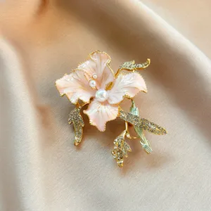 Exquisite enamel pink flower brooch detailed close-up shot with sparkling rhinestones and pearls.
