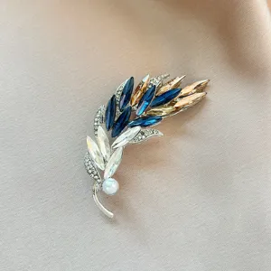 Exquisite crystal rhinestone feather brooch detail, featuring blue and champagne stones.