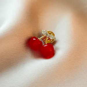 Élégante broche cerise rouge avec des strass étincelants et métal plaqué or pour femmes.