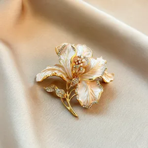 Exquisite enamel flower brooch featuring sparkling rhinestones and pearls. Vintage golden pin.