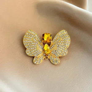 Close-up of a vintage gold-tone butterfly brooch with sparkling clear rhinestones and amber crystals.