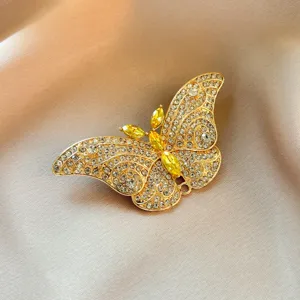 Closeup of a gold crystal butterfly brooch with sparkling rhinestones and yellow gems.