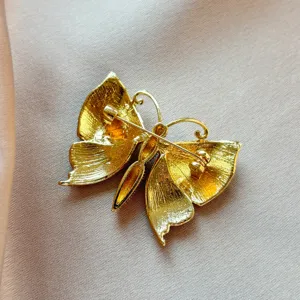 Close-up back view of a delicate gold-toned butterfly brooch, showing fine metalwork and pin.