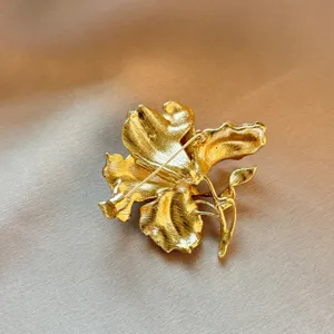 Gold floral brooch back detail, vintage metallic texture, elegant secure pin clasp design.
