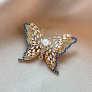 Vintage hollow-out crystal butterfly brooch pin with blue rhinestones and pearl for women.
