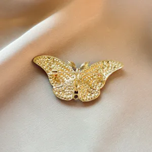 Detailed view of the gold butterfly brooch back mechanism, showing secure pin and textured finish.