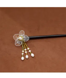 Gros plan de fleurs tissées à la main et de glands en perles sur une épingle en ébène.