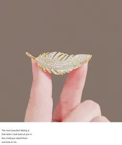 Exquisite gold feather brooch sparkling with full crystals, elegant suit lapel pin accessory.