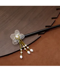 Détail d'une fleur tissée à la main et d'un gland en perles sur une épingle en ébène