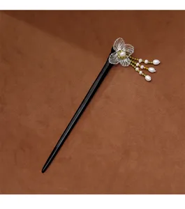 Détail d'une fleur tissée à la main et d'un gland en perles sur un pic à cheveux en ébène