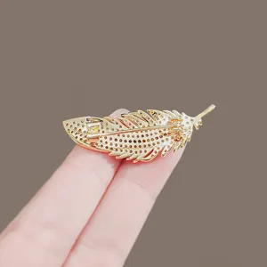 Elegant gold feather brooch with sparkling rhinestones, perfect suit accessory for women.