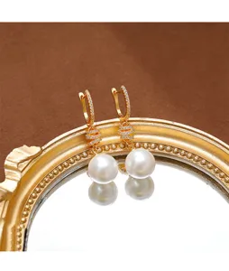 Primer plano detallado de elegantes pendientes de perlas chapados en oro con circón.