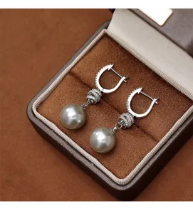 Primer plano detallado de elegantes pendientes de perlas con nudo de circonitas en estuche