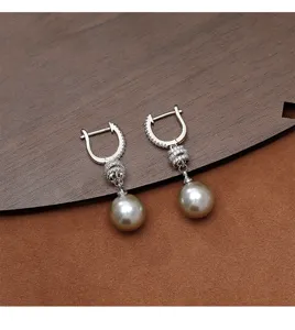 Primer plano de elegantes pendientes de aro plateados con perlas champagne y circonitas