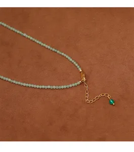 Detail view of handmade beaded necklace with green gemstones and gold lobster clasp.
