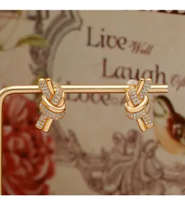 Detailed view of luxury gold knot stud earrings with sparkling pave-set clear crystals